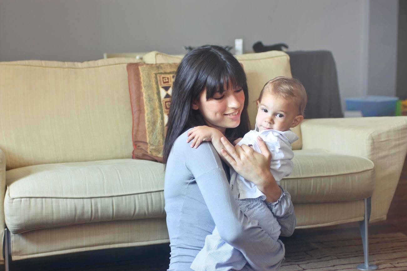 Una babysitter abbraccia teneramente un bambino sul divano di casa