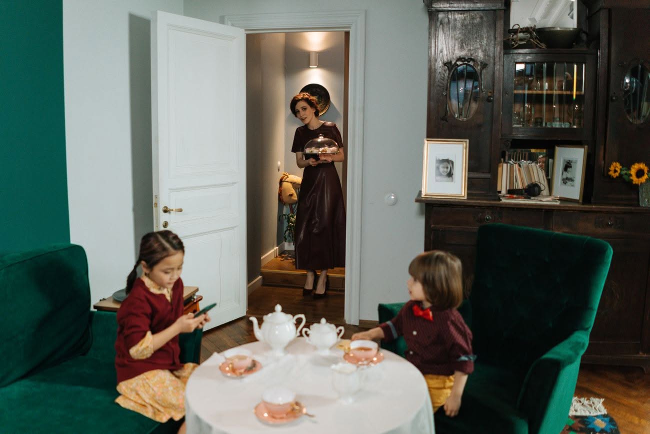 Una babysitter prepara la merenda a due bambini nel salotto di casa